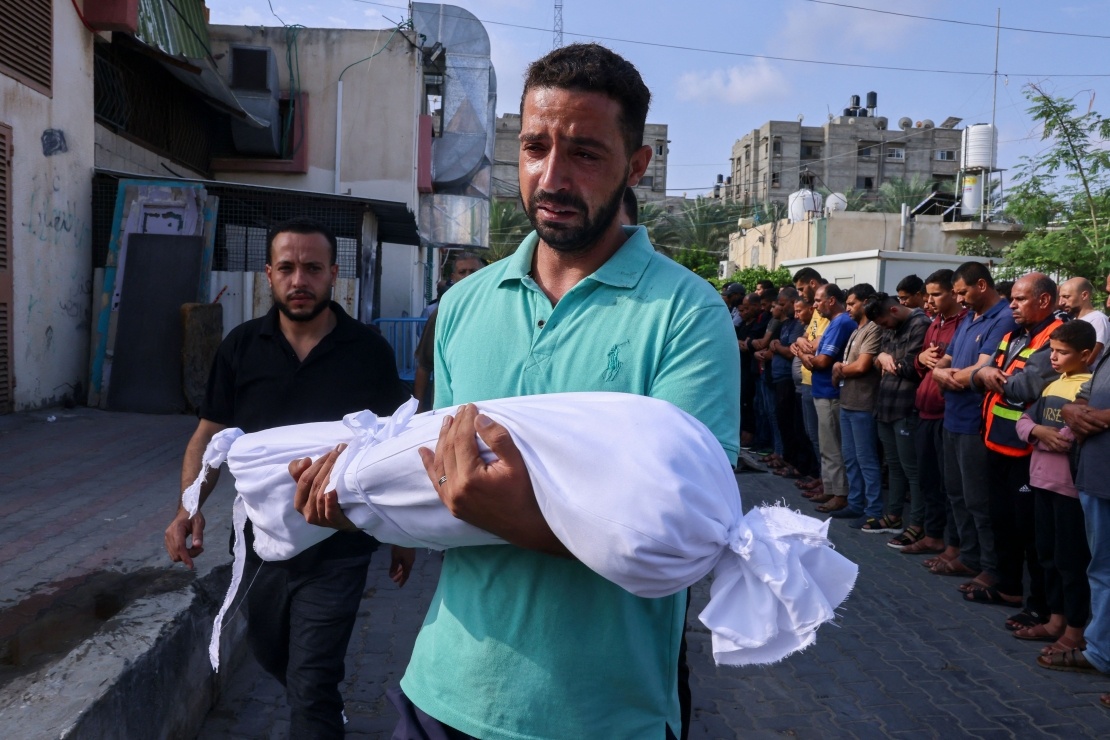 A Palestinian carries the body of a child who was killed during overnight shelling in Gaza on October 10, 2023.