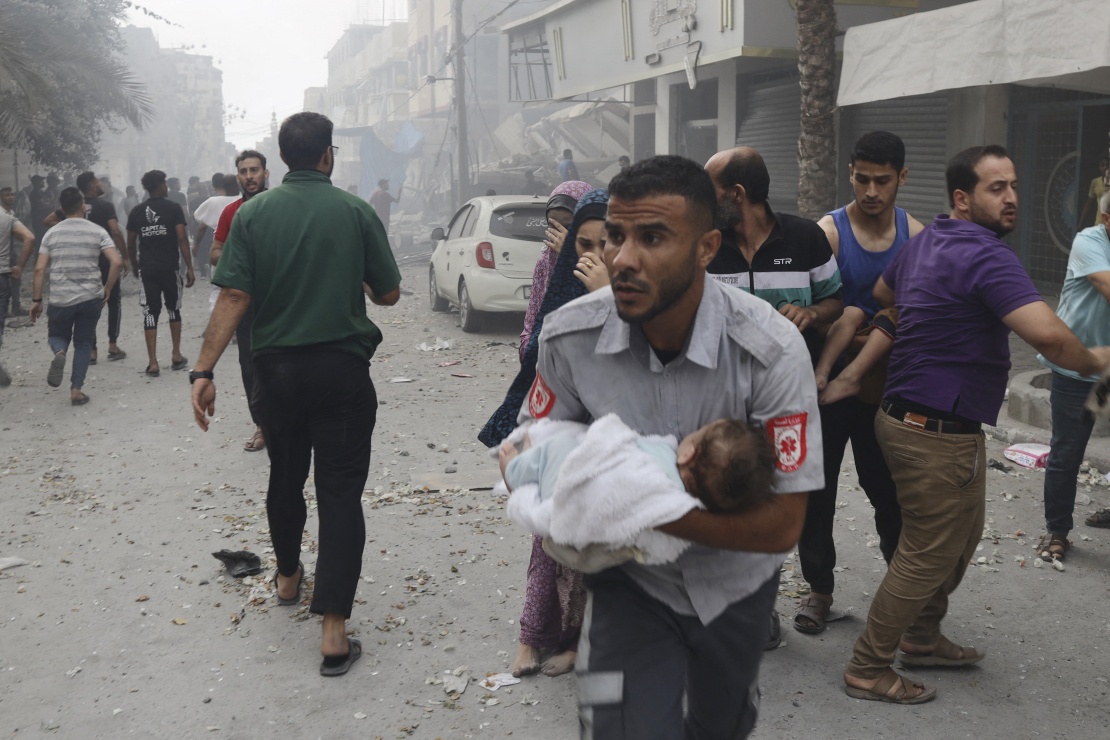 A member of the Palestinian Civil Defense runs with a child rescued from the rubble. Gaza City, October 9, 2023.
