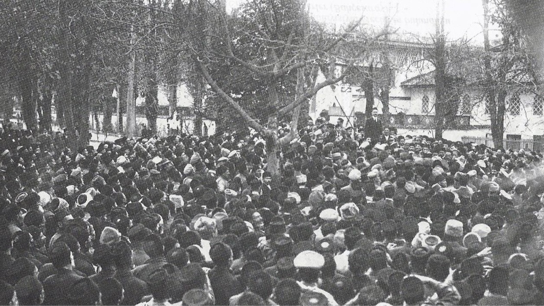 Збори кримських татар біля Бахчисарайського палацу восени 1917 року. Номан Челебіджіхан стоїть на узвишші під прапорами.&nbsp;