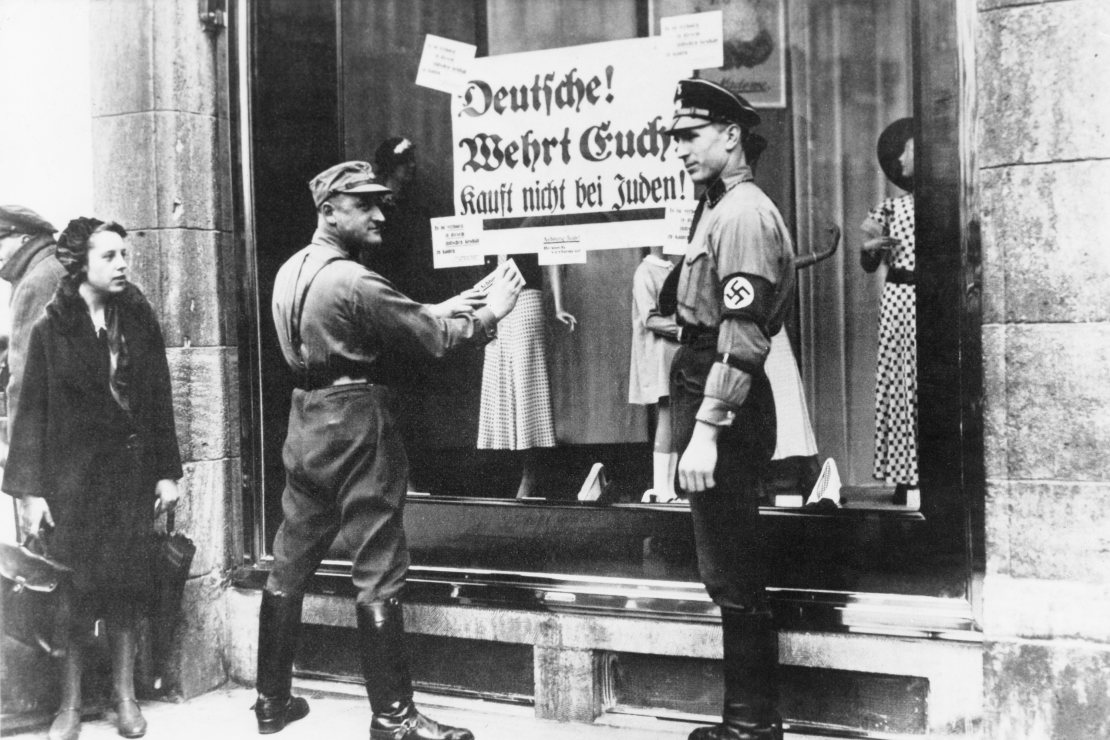 Штурмовики СС наклеюють антисемітські листівки на вітрину єврейського магазину в Берліні, 1933 рік.