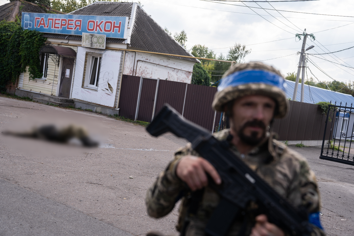 A soldier of the 33rd Assault Battalion in Sudzha. The body of a dead Russian soldier is behind him on the road.