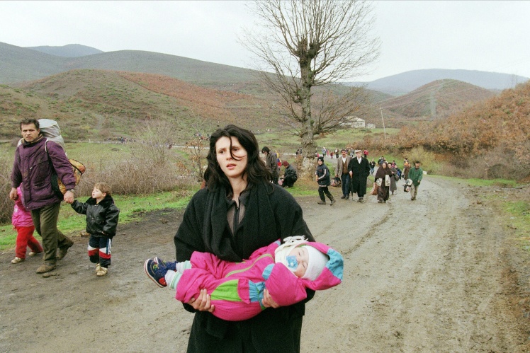 Жінка з немовлям тікає з Косова на територію Албанії, 3 квітня 1999 року.