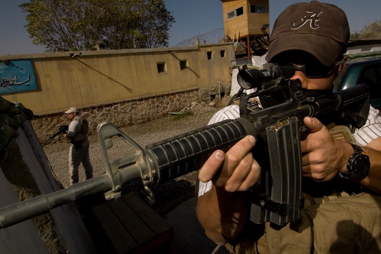 Приватний охоронний підрядник Ніл Гері, колишній морський піхотинець, займає оборонну позицію, забезпечуючи безпеку конвою 1 листопада 2005 року в Кабулі, Афганістан. Гері працював у приватній військовій компанії Crucible, яка забезпечує охорону підрядників Державного департаменту США.