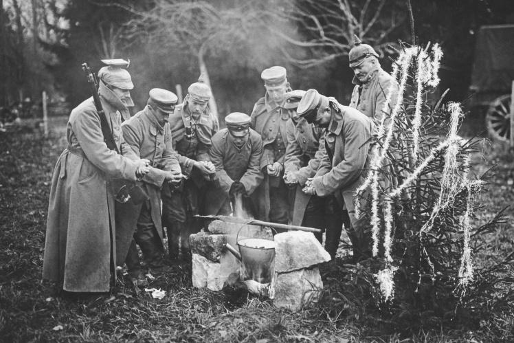 German soldiers warm their hands near a fire as they prepare rabbit stew for a New Yearʼs Eve dinner during World War I, 1916.