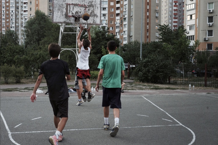 Children play basketball on the street playground in Pozniaky district.