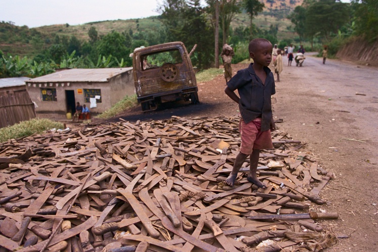 A boy stands on a pile of machetes, Rwanda.