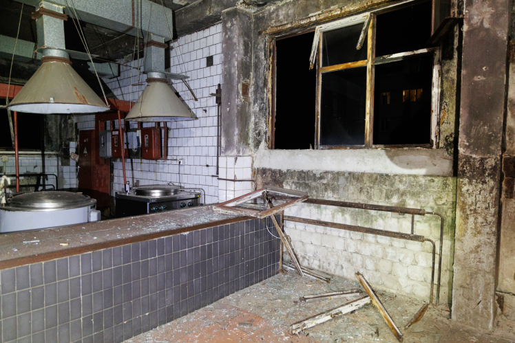 One of the broken windows of the canteen. There are fragments of glass and wooden windows on the floor and surfaces.