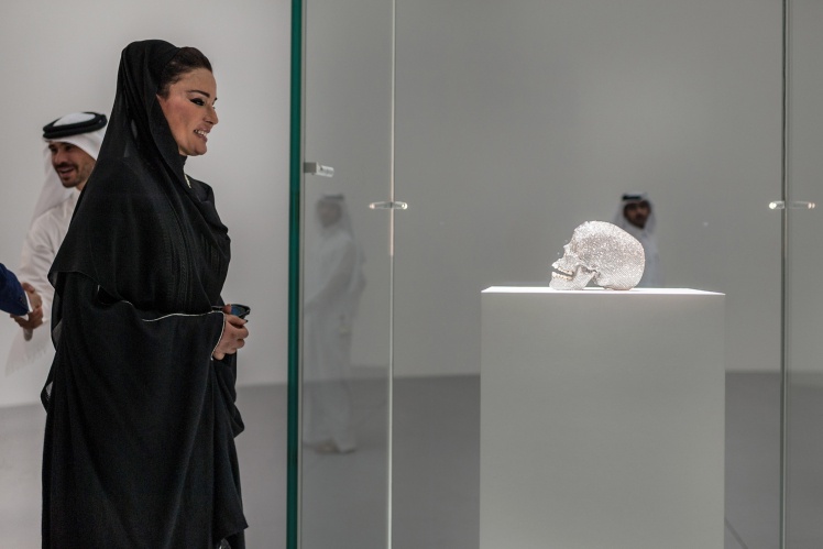 The wife of the Emir of Qatar Sheikha Moza bint Nasser al-Misned next to Damien Hirstʼs work "For the Love of God" at an exhibition in Doha, 2013.