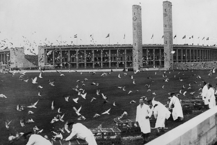 Голубів випускають у небо над стадіоном під час церемонії відкриття Олімпіади в Берліні, 1 серпня 1936 року.