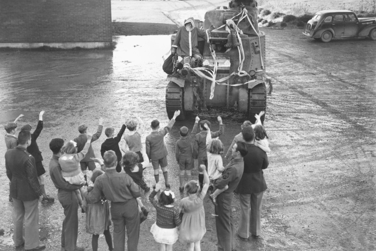 A soldier in the role of Santa arrives on a tank to greet British orphans, December 1942.