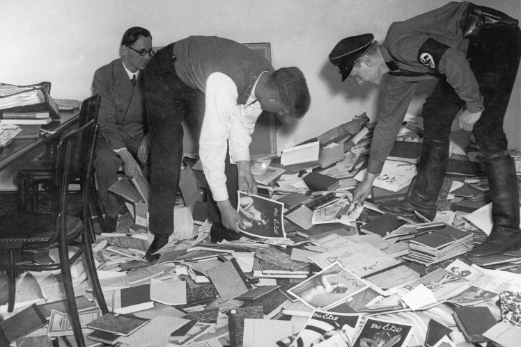 Студент і нацистський штурмовик сортують літературу  розграбованої бібліотеки Інституту сексуальних досліджень у Берліні, 6 травня 1933 року.