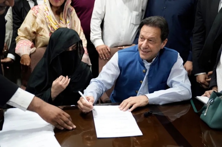 Імран Хан (праворуч) та його дружина Бушру Бібі (ліворуч) підписують документи у Високому суді Лахора, Пакистан.
