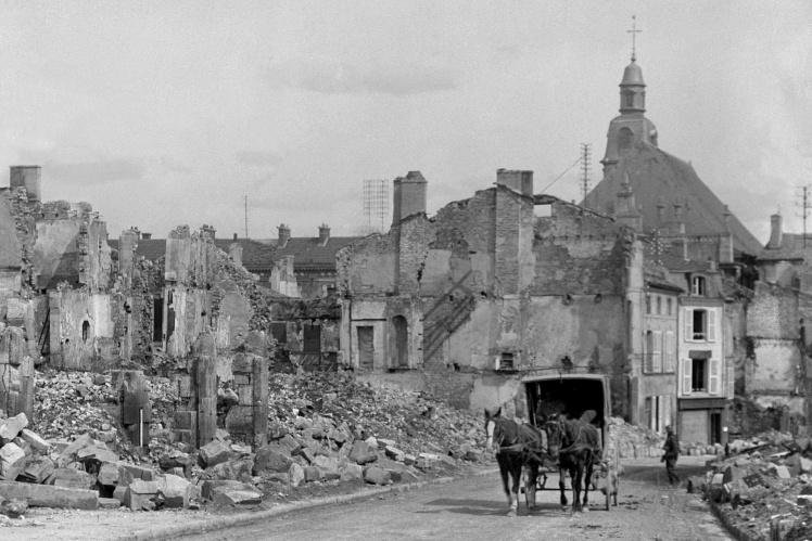 A horse-drawn carriage passes among the destroyed buildings of Verdun after the shelling, 1916.