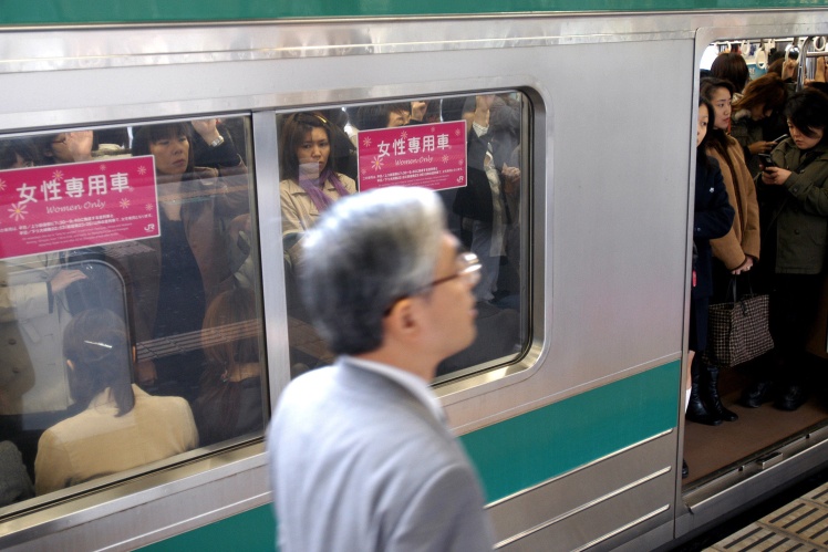 Японець проходить повз переповнений жіночий вагон у метро Токіо.