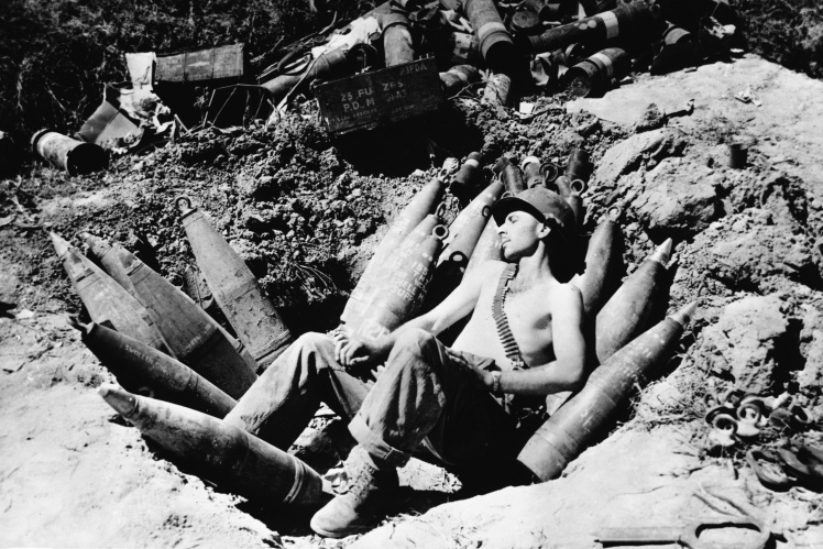 An American gunner rests among shells at a position near the 38th parallel, 1951.