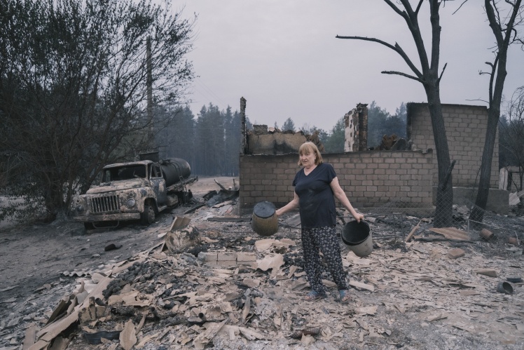 A villager disassembles the ruins of a burnt house.