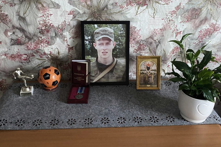 Мама Вадима поряд з портретом сина тримає його футбольні нагороди.