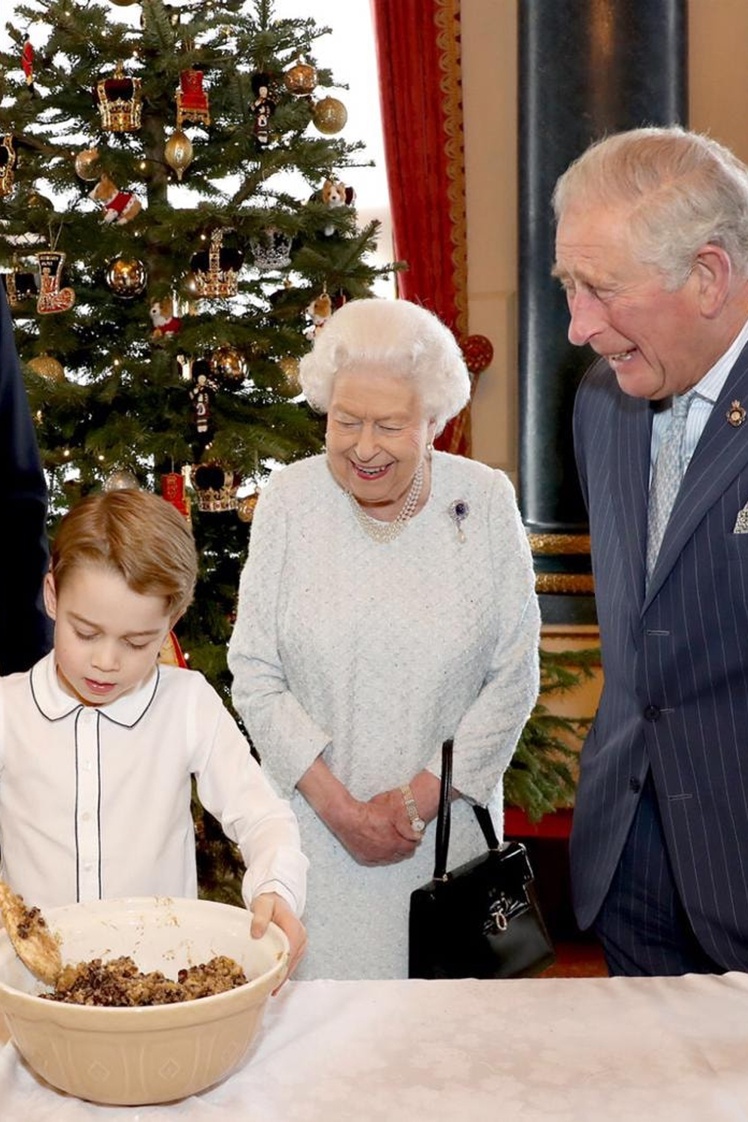 Єлизавета ІІ та нинішній король Великої Британії спостерігають, як принц Джордж готує різдвяний пудинг.