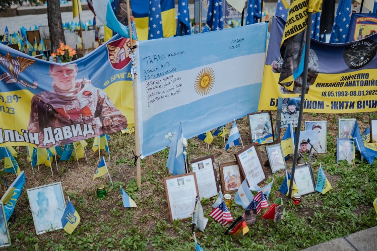 The Argentine flag bears the names of five foreign soldiers who died fighting for Ukraine. Beneath the flag are their biographies. The flag obscures the portraits of the soldiers who stood there before it appeared.