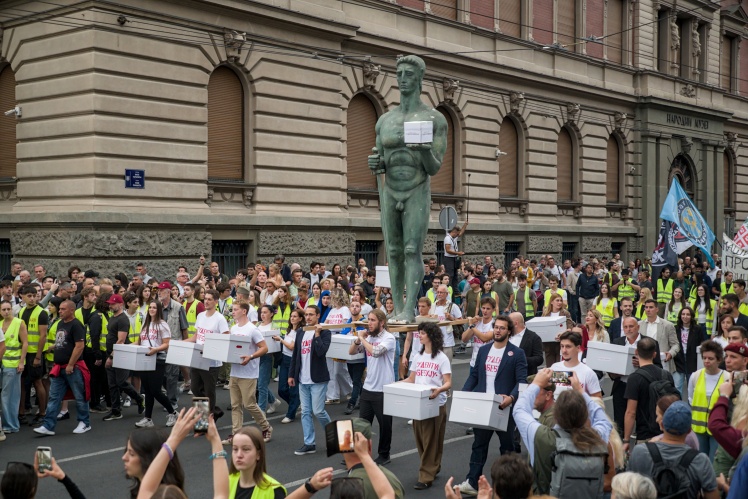 Студенти несуть коробки з підписами на реєстрацію свого списку та копію белградського памʼятника «Переможець». Белград, 14 вересня 2026 року.