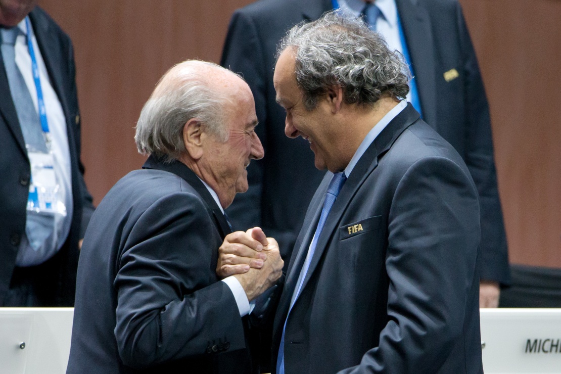 Президент ФИФА Йозеф Блаттер (слева) жмет руку президенту УЕФА Мишелю Платини (справа) во время Конгресса ФИФА 29 мая 2015 года в Цюрихе.
