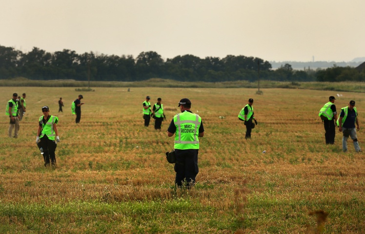 Следователи по делу МН17 исследуют место падения самолета в поисках тел.