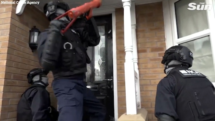 Британские полицейские выбивают дверь квартиры одного из преступников.