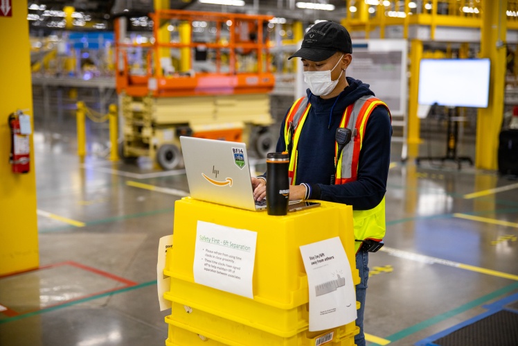 Сотрудники Amazon в перчатках и защитных масках работают на одном из складов компании.