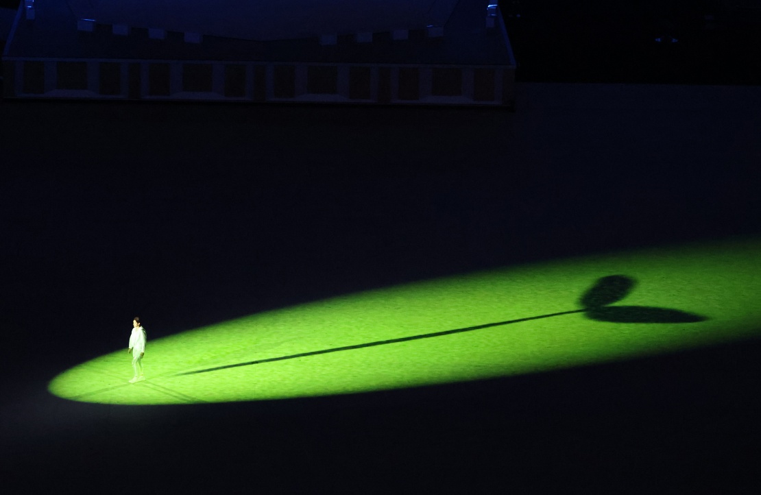 Церемонія відкриття на Олімпійському стадіоні. Спортсмен стоїть у промені світла під час виступу, 23 липня 2021 року, Токіо.