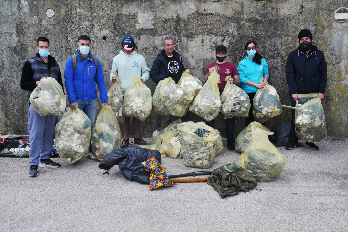 Добровольці з асоціації I pirati della Plastica і «Сини океану» позують для фото з пакетами, заповненими пластиком, знайденим у воді гавані, 18 квітня 2021 року, Ліворно, Італія.