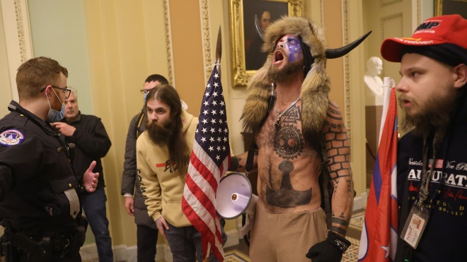 Парень в мехах и с рогами на штурме Капитолия ― вы точно видели это фото! Это Джейк Анджели ― лицо движения, которое верит в «демократов-педофилов-сатанистов», пьющих кровь. И нет, это не шутка