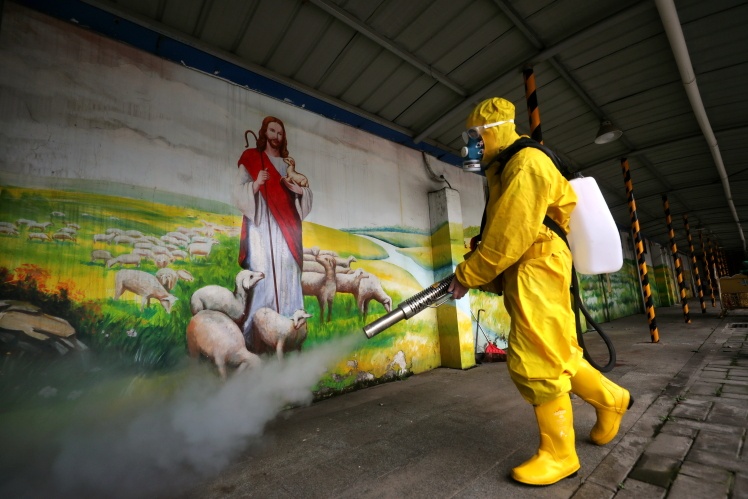 Волонтер у жовтому захисному костюмі дезінфікує церкву в Ухані, 6 березня 2020 року.