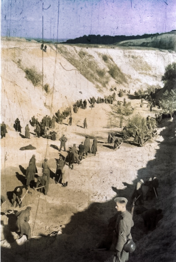 Советские военнопленные под наблюдением немецких солдат засыпают землей тела расстрелянных евреев.