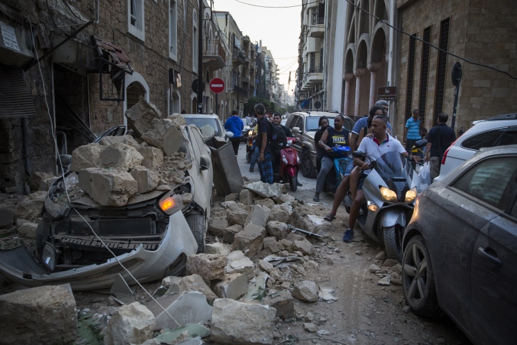Жители Бейрута проезжают мимо машины, на которую обрушилась стена дома.