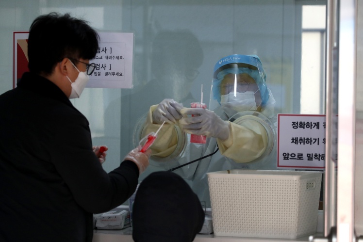 Медичний працівник бере зразки у людей в центрі попереднього тестування в Сеулі, 12 грудня 2020 року.