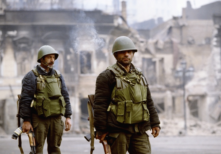 Два грузинских солдата стоят среди разрушенных бомбардировками зданий в Тбилиси во время гражданской войны в Грузии.
