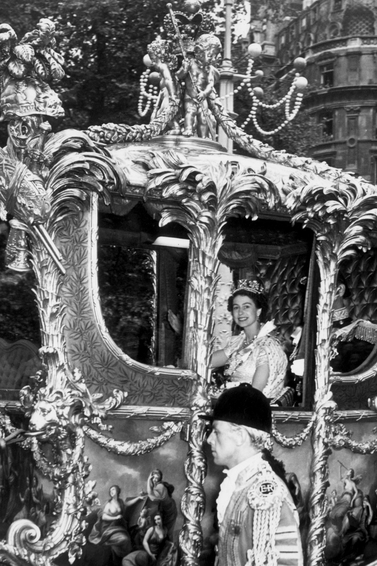 Елизавета ехала в специальной карете Gold State, позже она жаловалась, что поездка была очень некомфортной и она «все время подпрыгивала на жестких сиденьях». На фото: Елизавета и ее муж принц Филипп едут на коронацию.