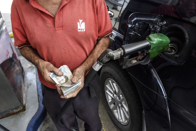 Сотрудник считает банкноты на заправочной станции Petroleos de Venezuela SA в Каракасе, 3 августа 2018 года.