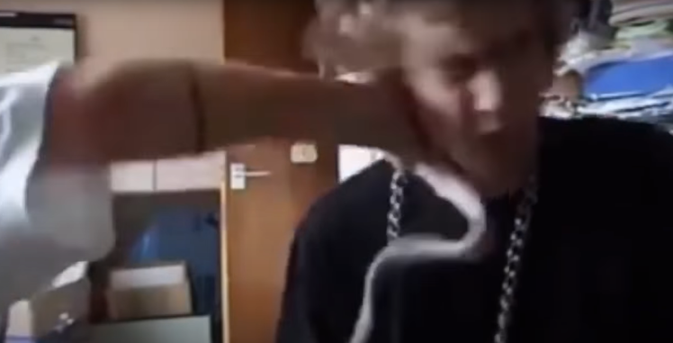 Скриншот из видео, в котором Уидона бьют в лицо.