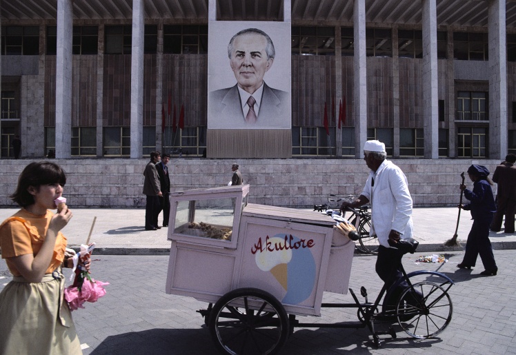 Продавец мороженого и пешеходы проходят мимо здания с портретом Энвера Ходжи, 1980 год.