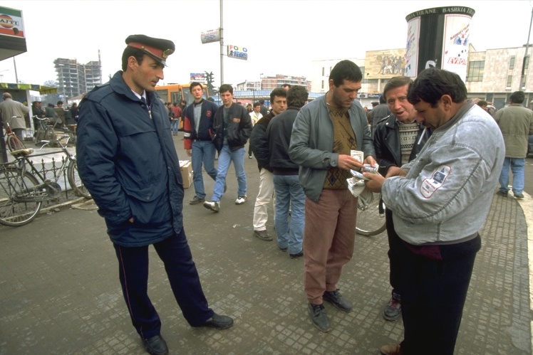 Полицейский в Тиране наблюдает за уличными валютными менялами, которые наживались на нестабильности курса национальной валюты из-за краха финансовых пирамид, начало февраля 1997 года.