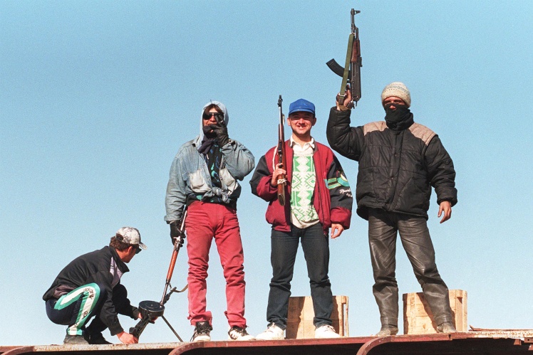 Вооруженные албанские повстанцы стоят на крыше сгоревшего автобуса неподалеку от Тираны, 12 марта 1997 года.
