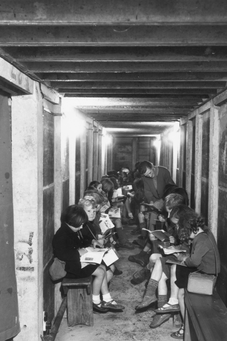 Вчителька перевіряє завдання під час уроку в бомбосховищі однієї зі шкіл Лондону, 1941 рік.